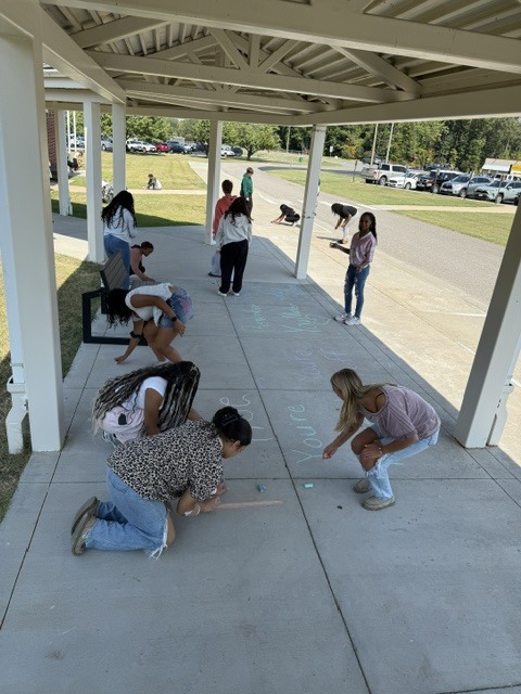 Students drawing positive messages on the sidewalk