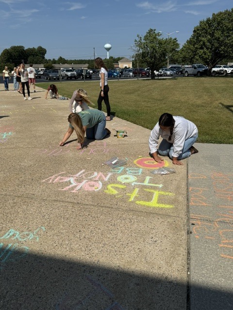 Students drawing positive messages on the sidewalk