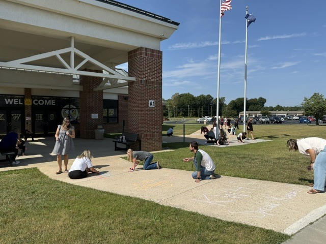 Staff drawing positive messages on the sidewalk