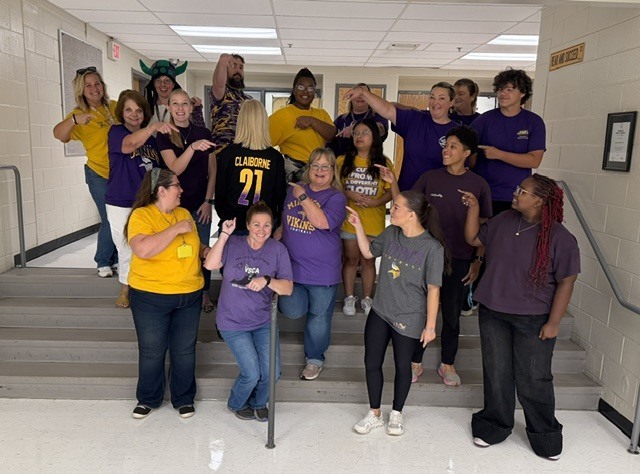 Staff pointing at Principal Barrick with a special jersey for Claiborne