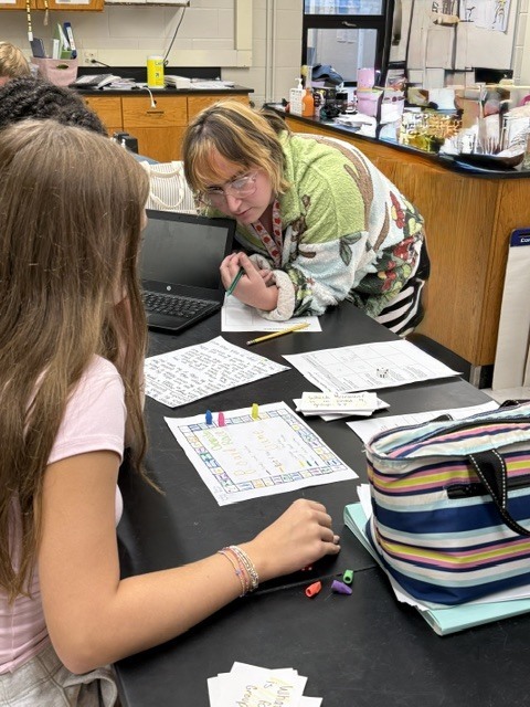 Ms. Candage helping to review a student's game board