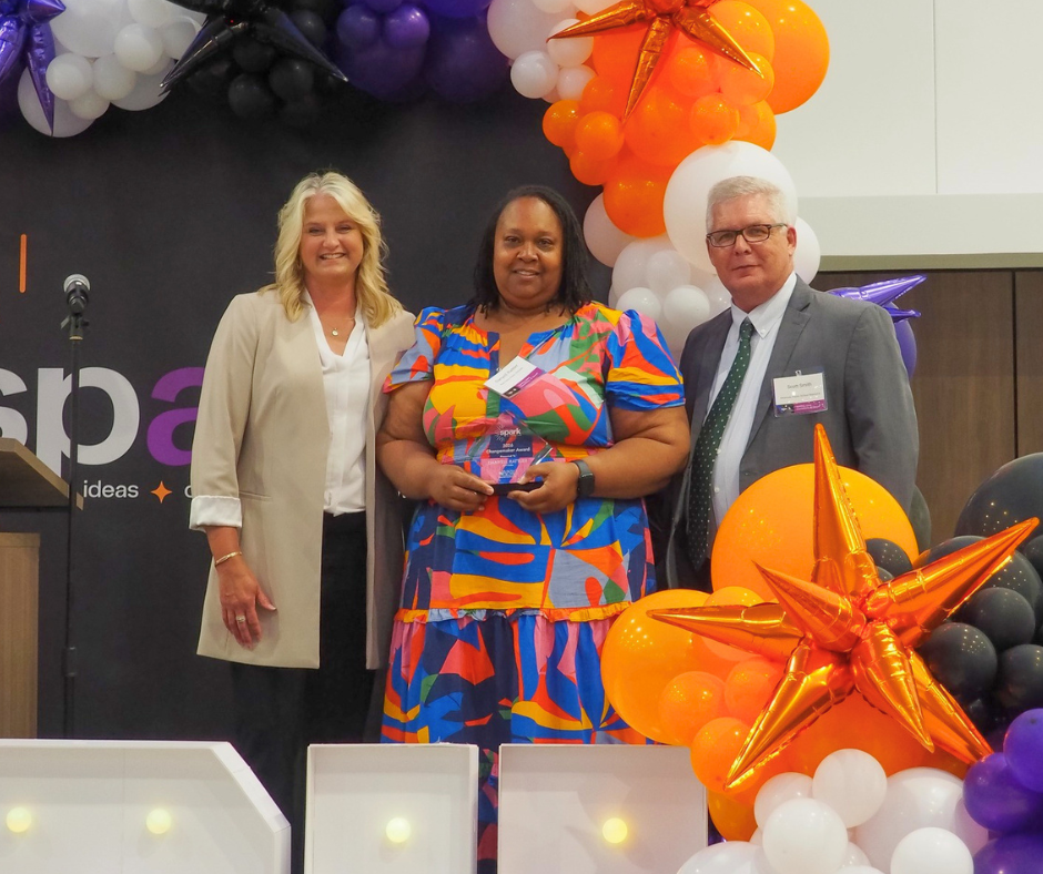 Danyell Rattler (SPED Director) receiving Arkansas Charter School Changemaker Award from Jeana Williams and Scott Smith (APSRC) at Spark2026 Symposium