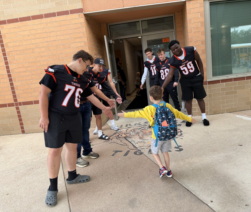 Football players greeting KPS Students.