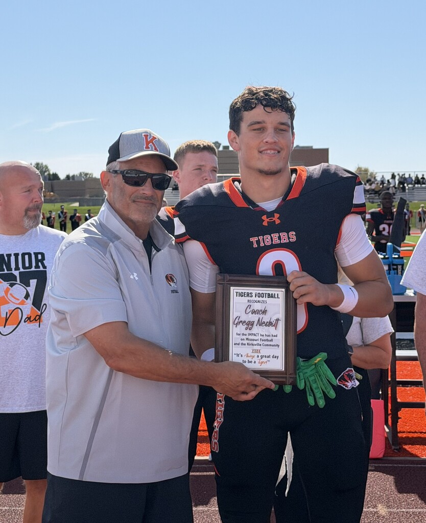 Coach Nesbitt holding his plaque with grandson, Blake.