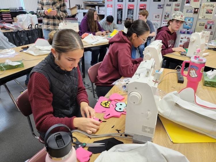 high school students working on sewing project 