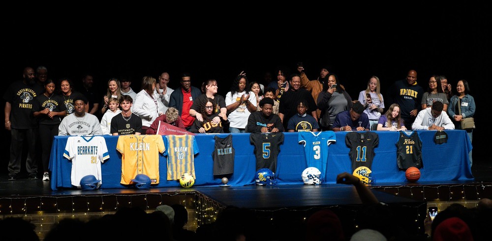 Klein High Signing Day - Students on Stage with families signing papers 