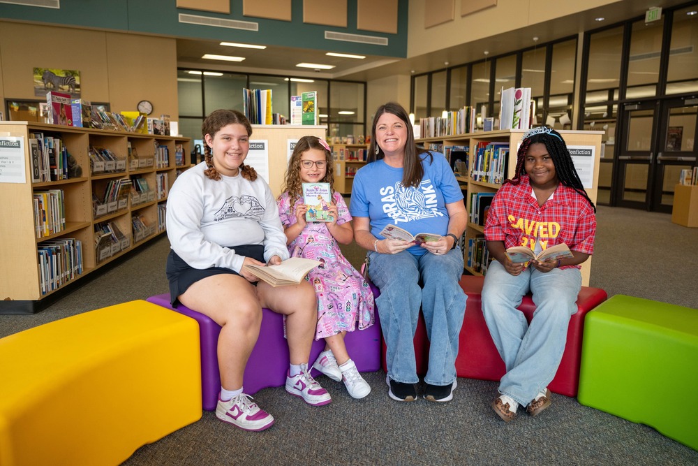 Kylie Zessin sits with students holding books in a library