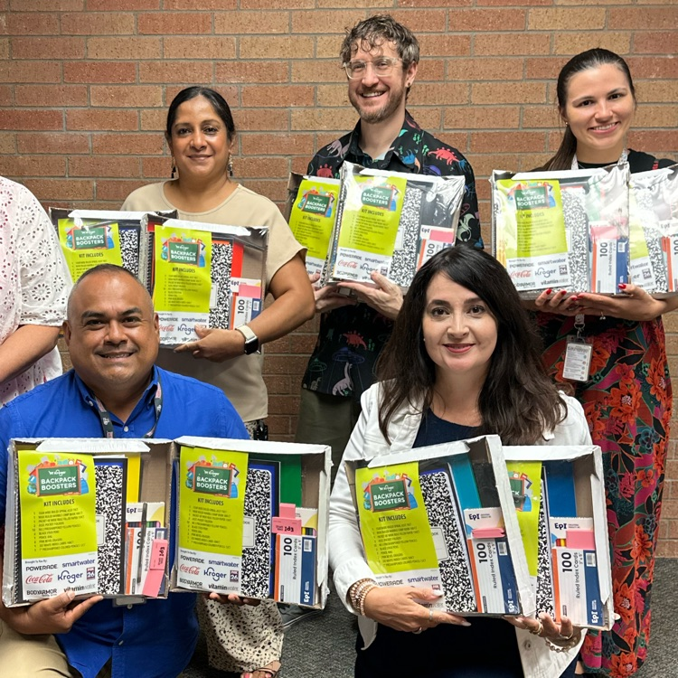 teachers holding packets of school supplies
