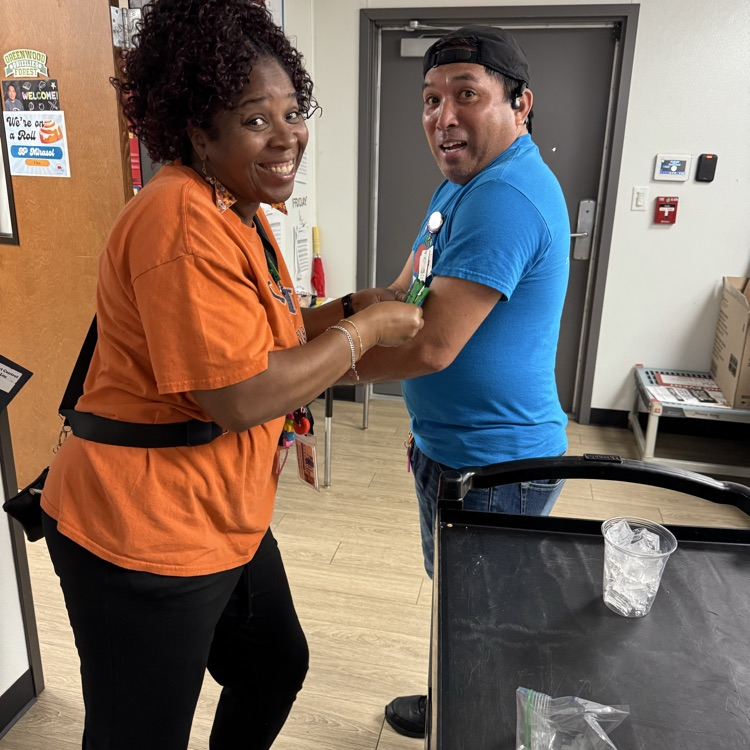 teacher in orange shirt playing game with food manager in blue shirt