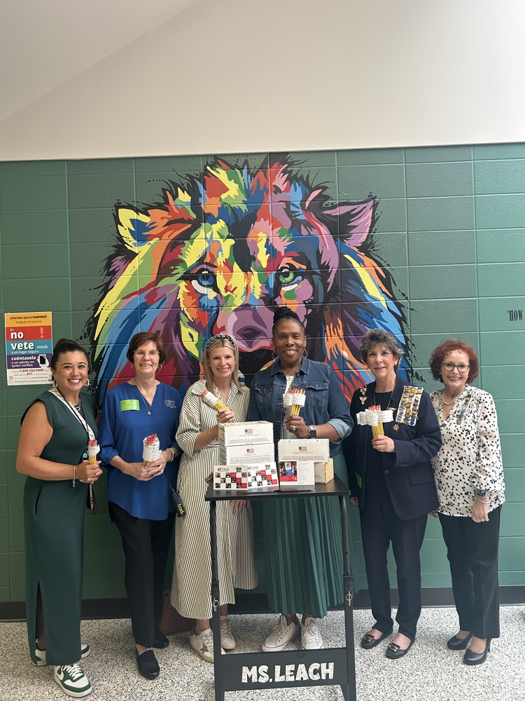 A group of ladies holding the pencil and tissue box donations. 