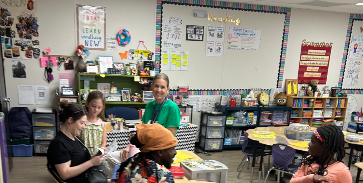 Teacher in green shirt sharing evidence of student learning with parents. 