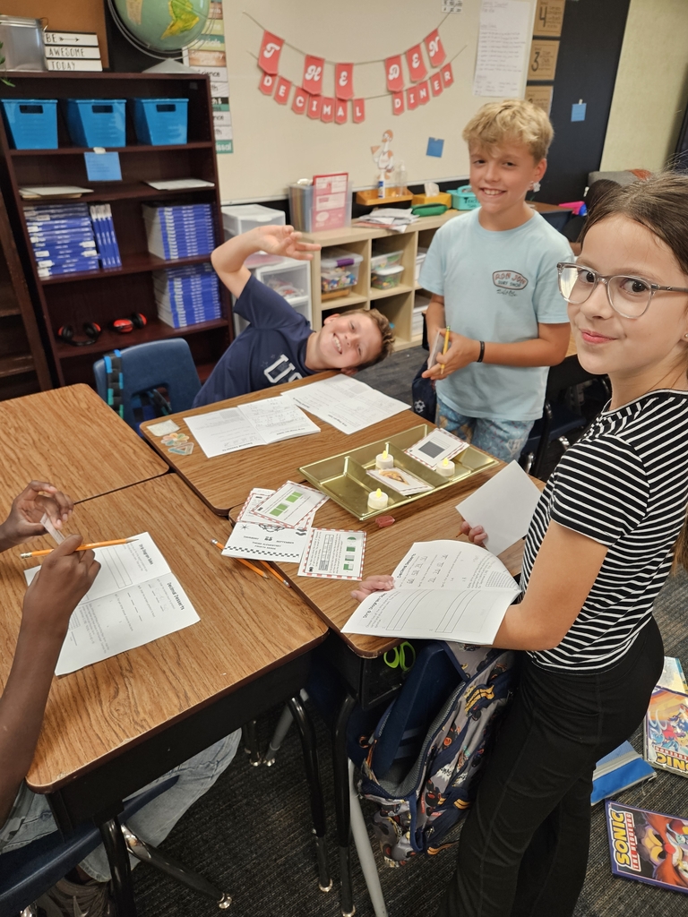 3 students working at their desk on math with a banner for The Tiger Den in the background.