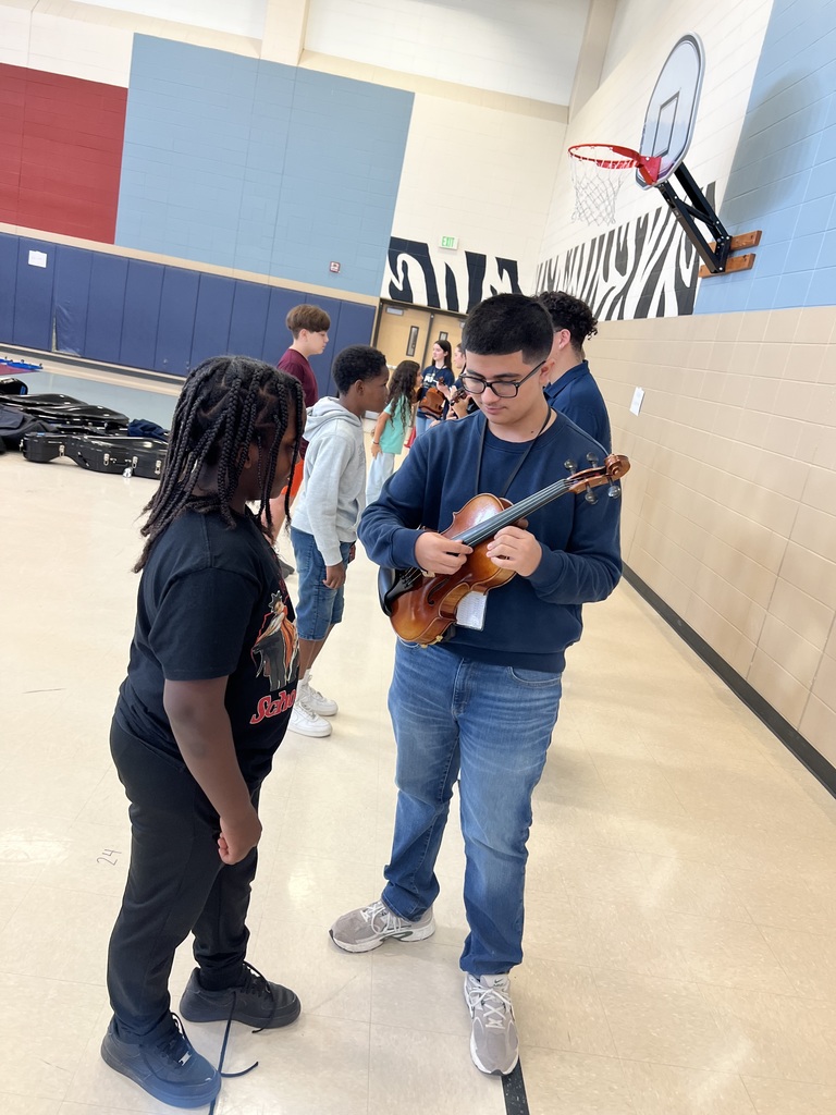High school student showing a 5th grader how to hold an instrument