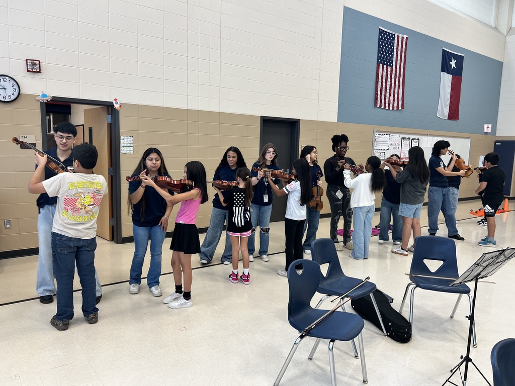 Group of high school students showing a 5th graders how to hold an instrument