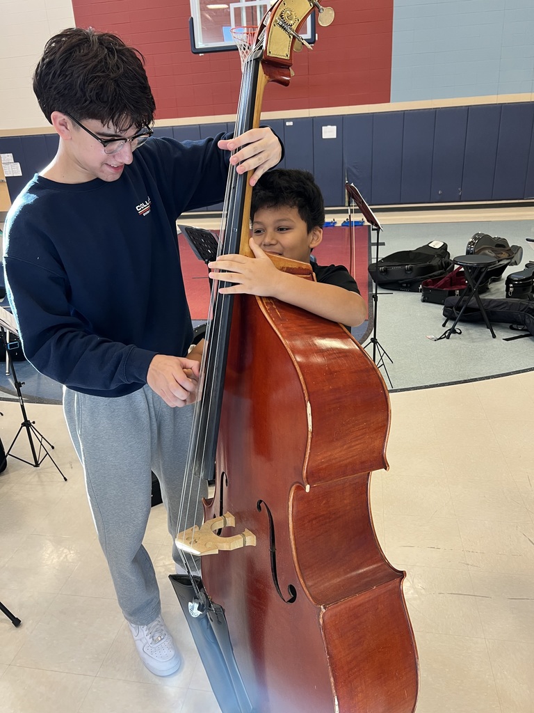 High school student showing a 5th grader how to hold an instrument