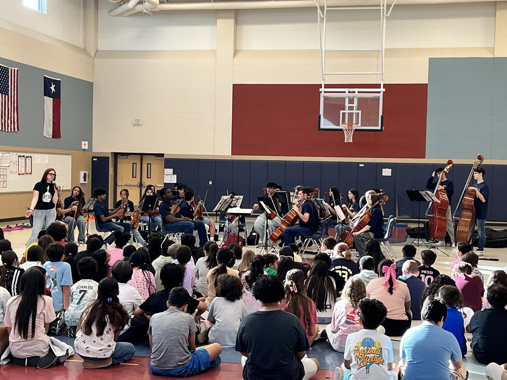 High school orchestra performing for a group of 5th grade students
