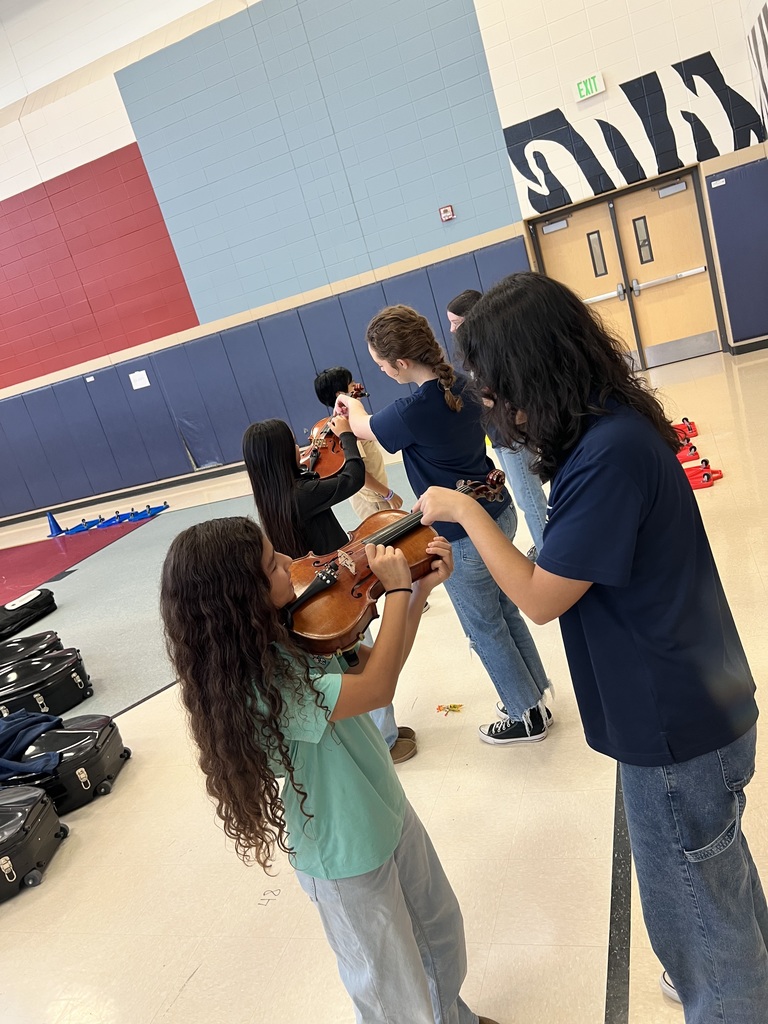 High school student showing a 5th grader how to hold an instrument