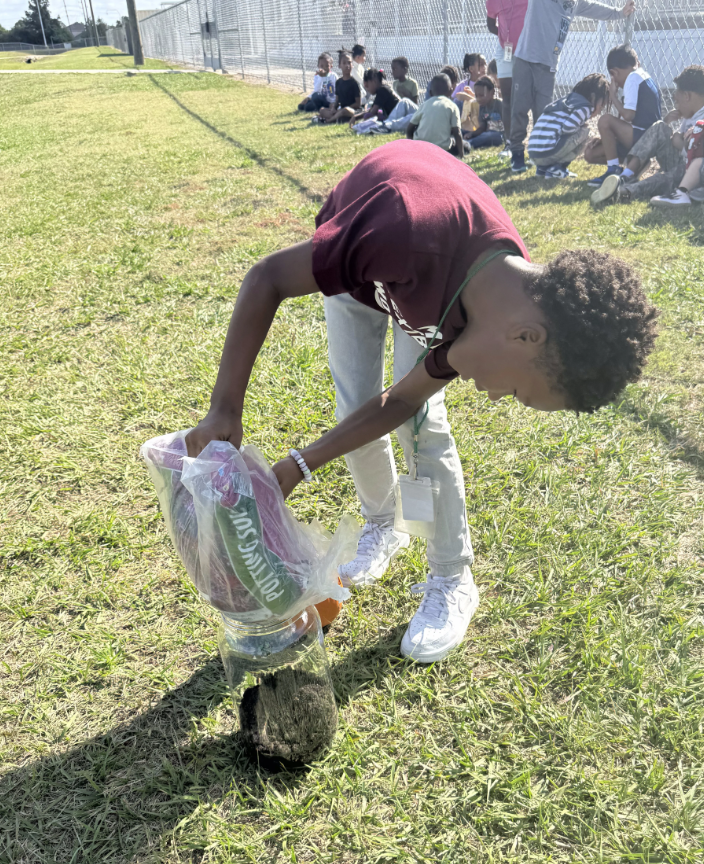 male student in maroon shirt planting pumpkin seeds 