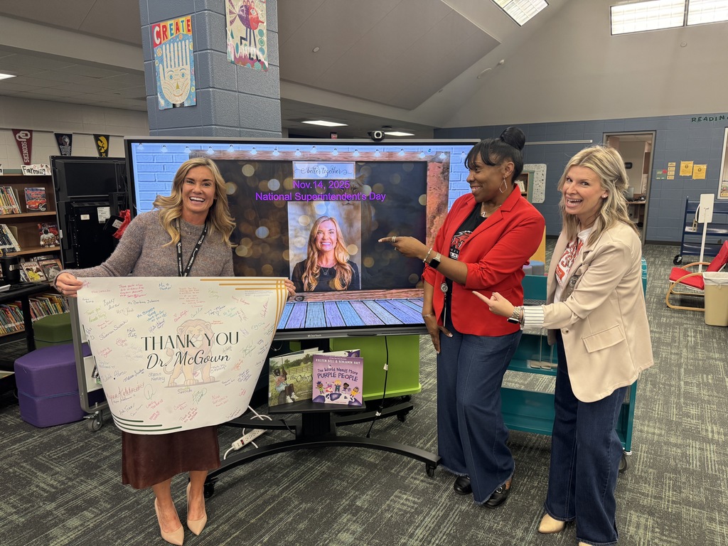 Superintendent showing off banner and her picture on slide 