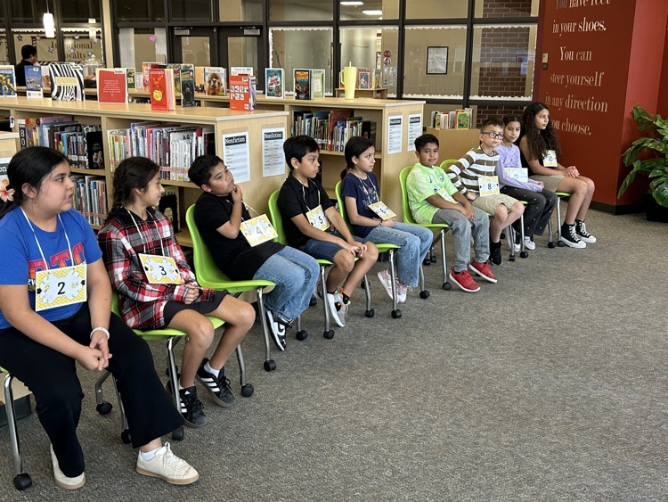 Spelling Bee contestants sitting in chairs waiting for next round to begin
