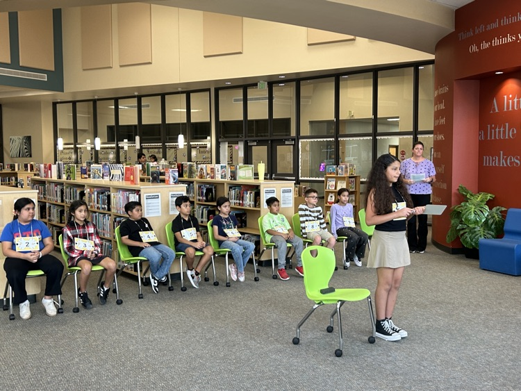 one contestant is standing in front of other contestants spelling her word