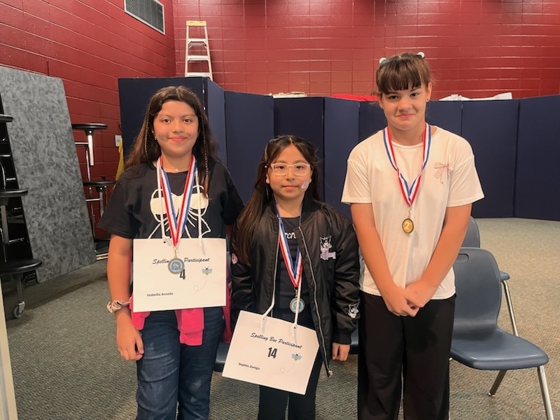 three students wearing spelling bee medals