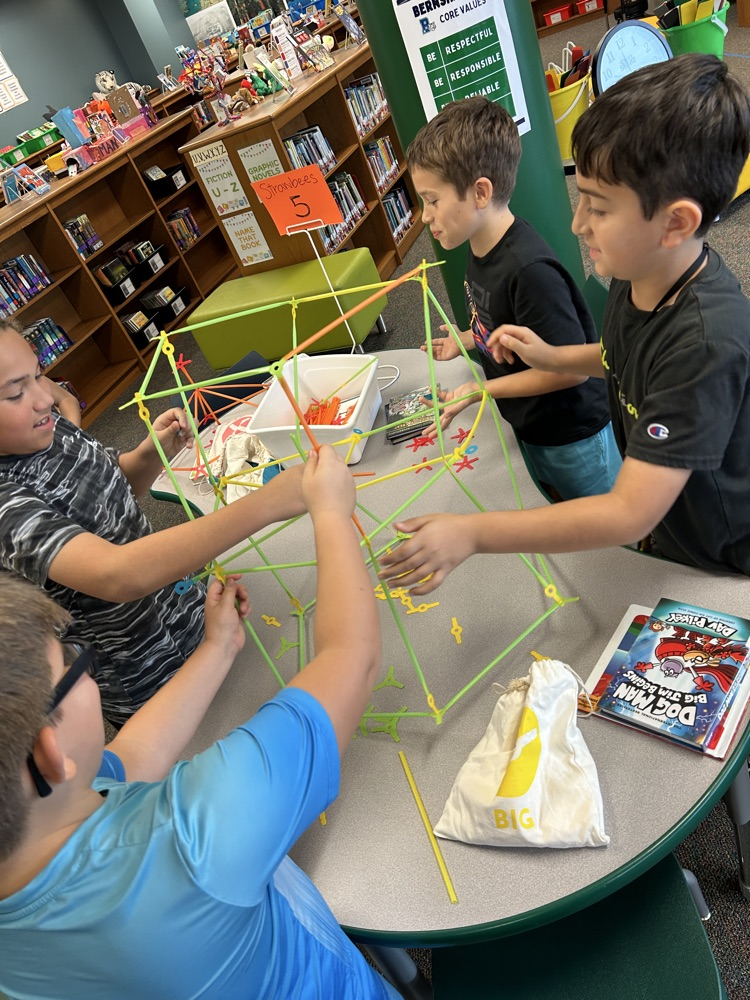 4 boys working together to build a structure with strawbees