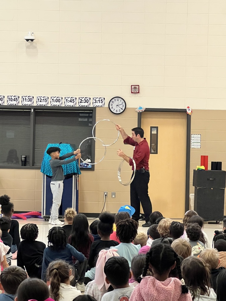 Magician performing trick in front of students while another student assists with large rings