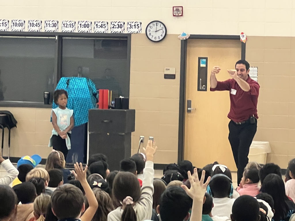 Magician performing trick in front of students while another student stands at the front of the crowd
