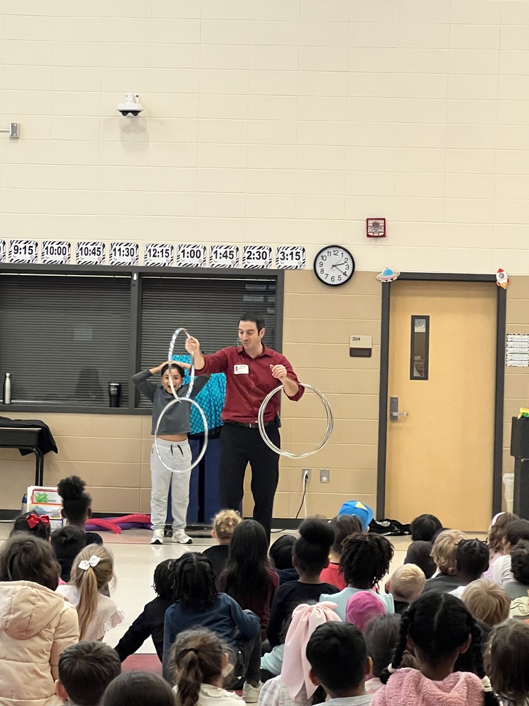 Magician performing trick in front of students while another student assists with rings