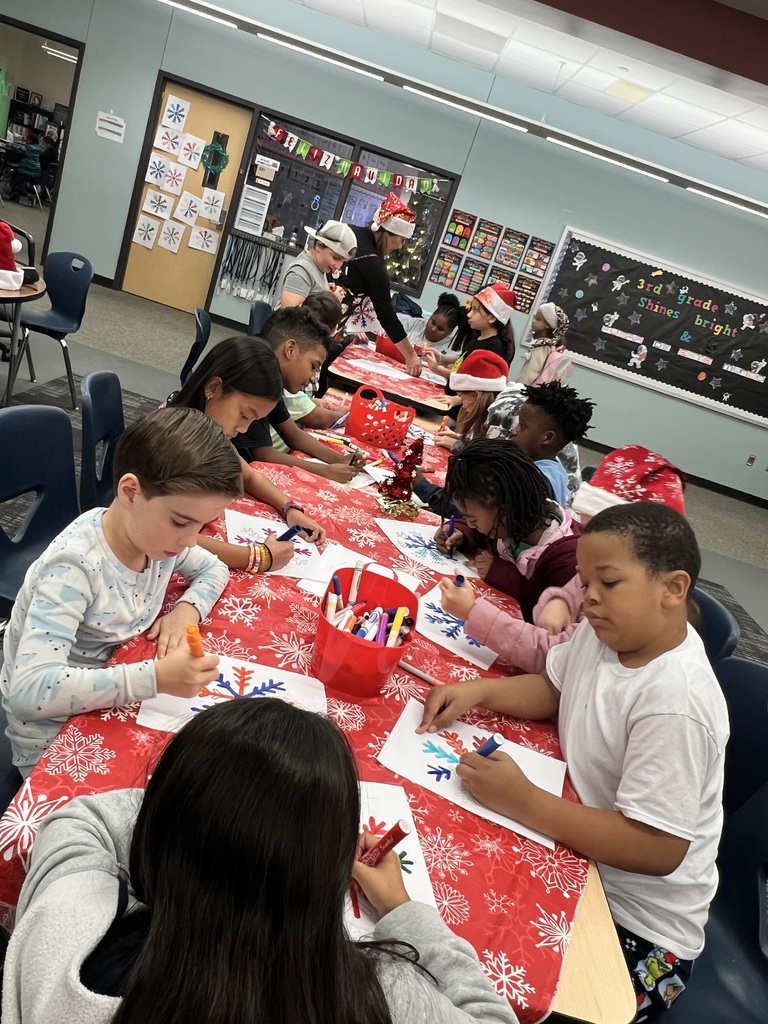 Students are sitting at tables coloring snowflake pictures