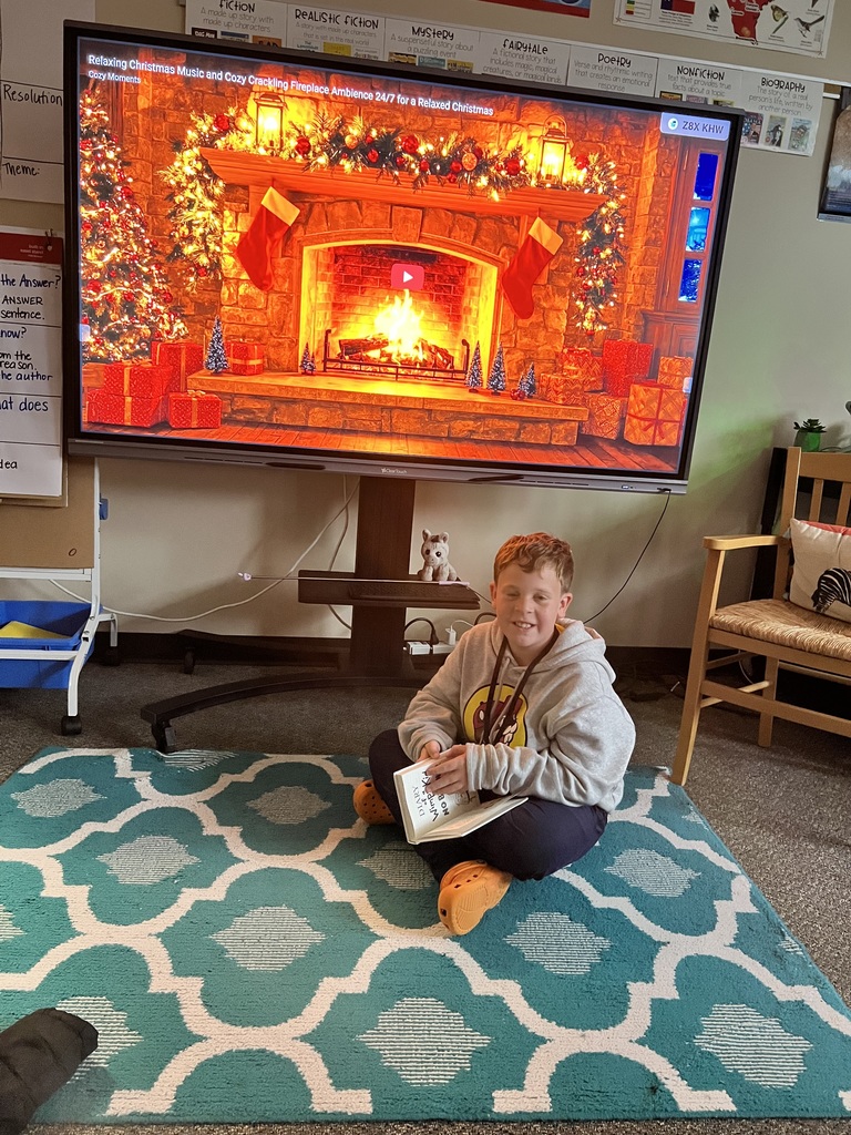 A student is on the floor reading beside a digital fireplace scene