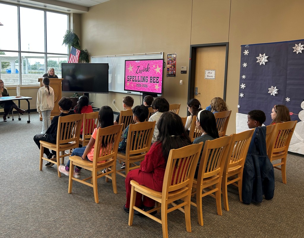 Spelling Bee contestants sit in chairs watching a speller get her word.