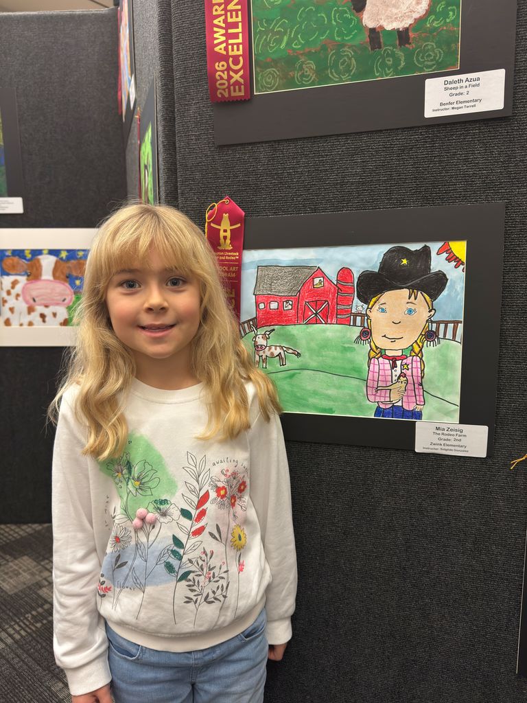 Student posing in front of student art work