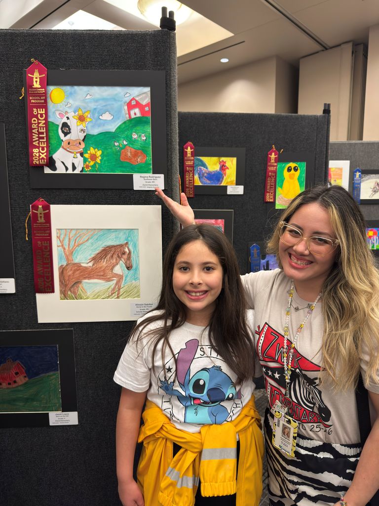Student and teacher posing in front of student art work