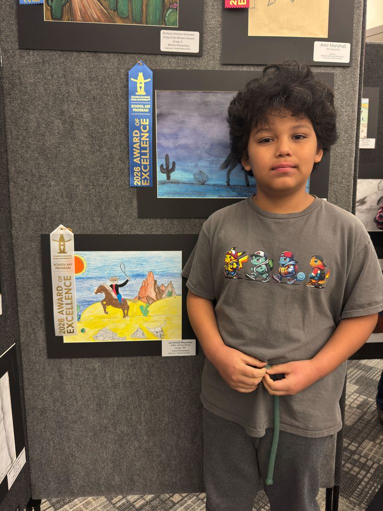 Student posing in front of student art work