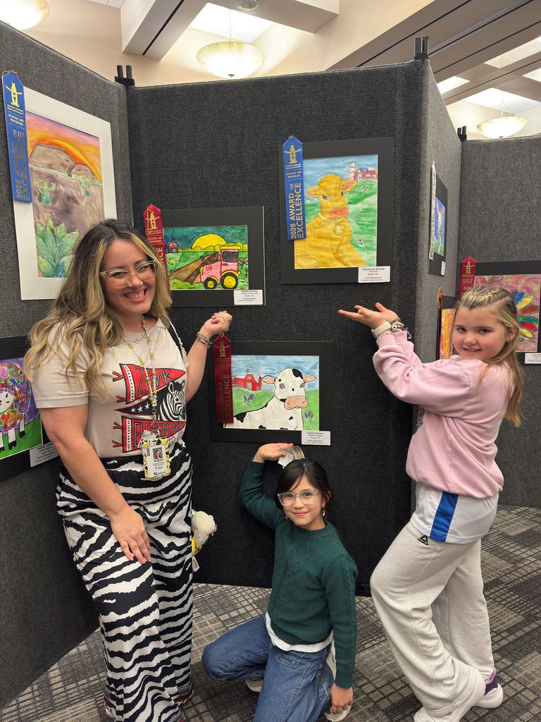 Students and teacher posing in front of student art work