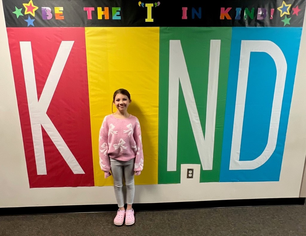 student posing inside the KIND sign as the "i"