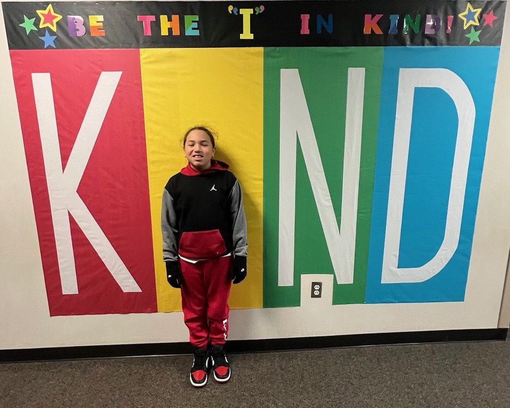 student posing inside the KIND sign as the "i"