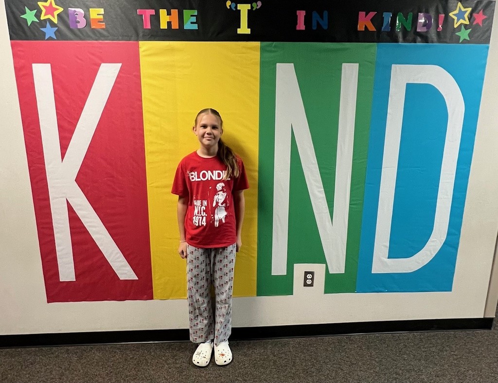 student posing inside the KIND sign as the "i"
