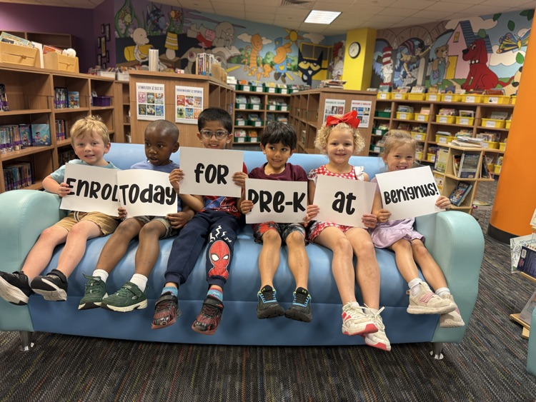 students holding signs that say enroll for PreK