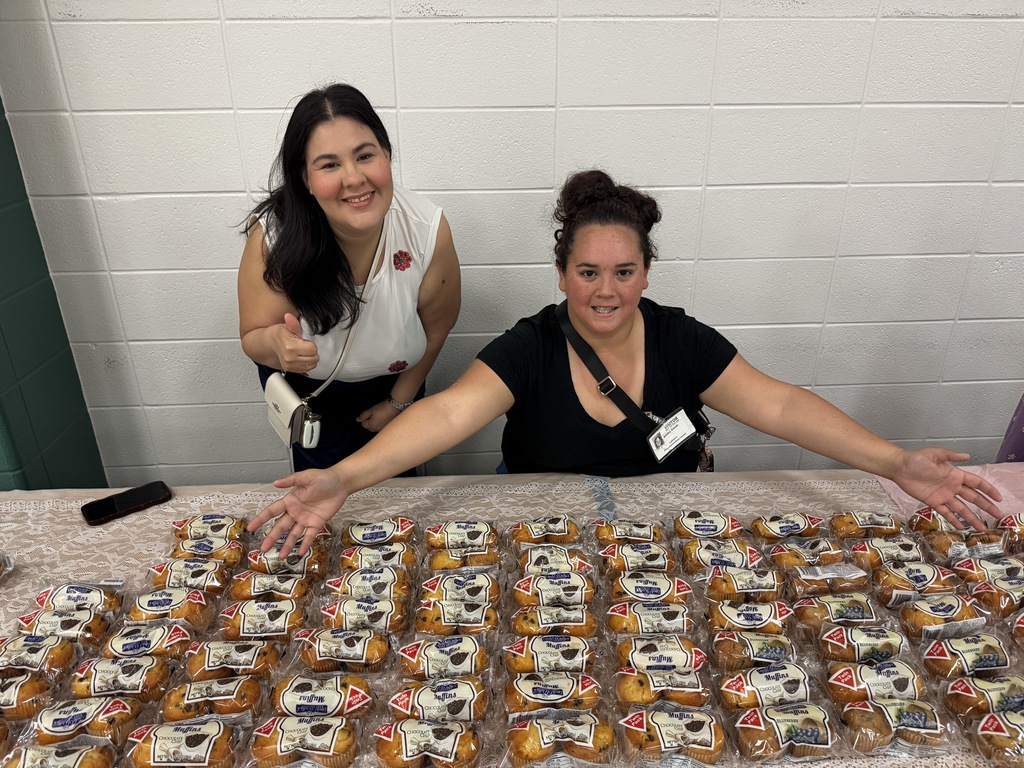 2 Ladies with lots of muffins set out for families to enjoy.