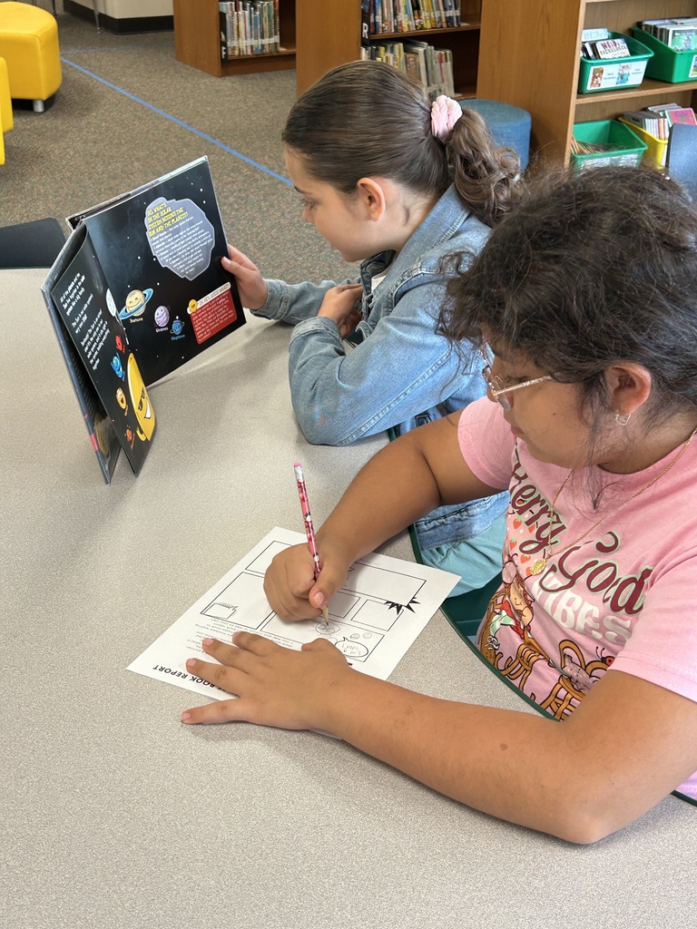 one girl is reading a book while the other sketches the content