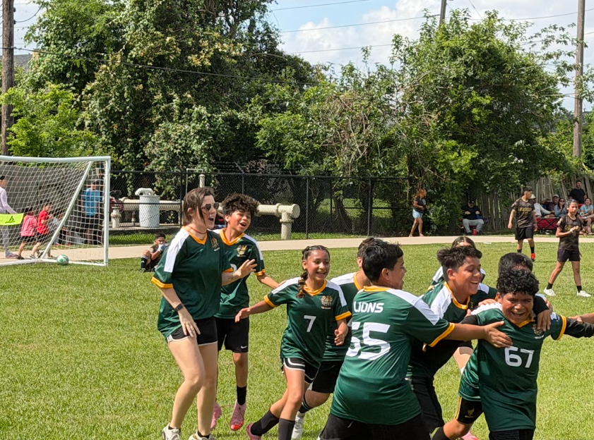Group of soccer players and their coach celebrating a score.