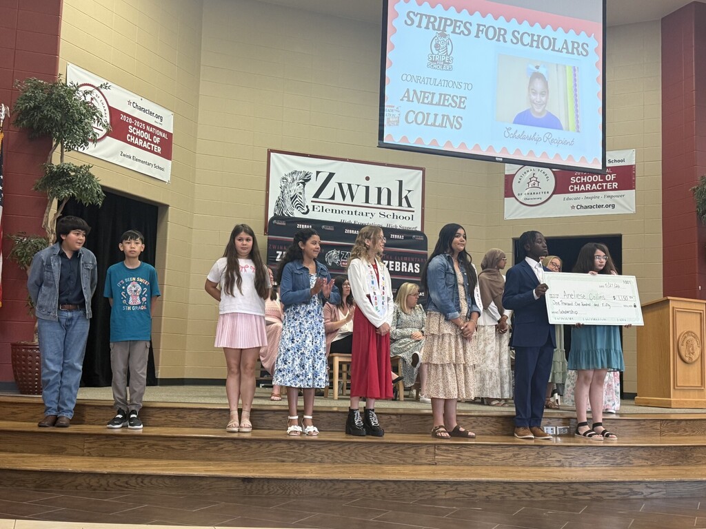 5th grade students on stage preparing to present a large check