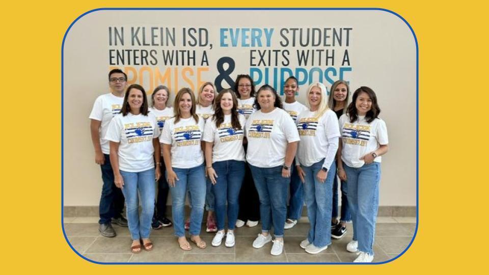 A group of people stand together in matching shirts with a slogan on a yellow background.
