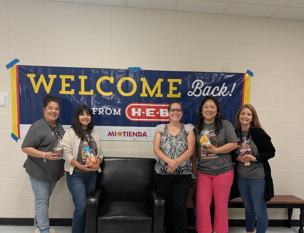 Five women stand in front of a blue banner reading "Welcome Back!" from H-E-B. They hold food items and pose for a photo.