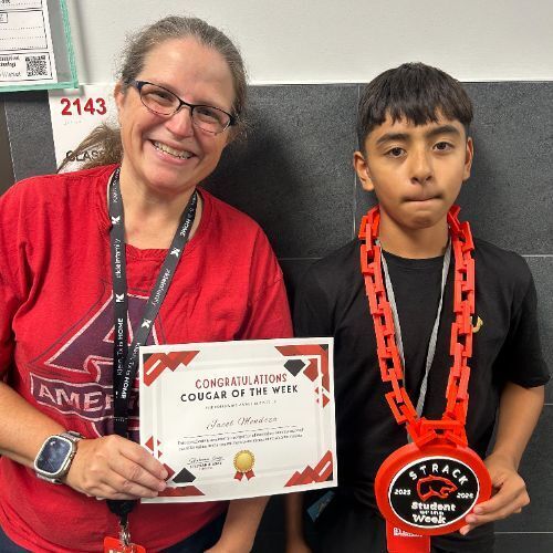 Adult woman and boy standing with red medals and certificate. Behind them is a wall with a number 2143.