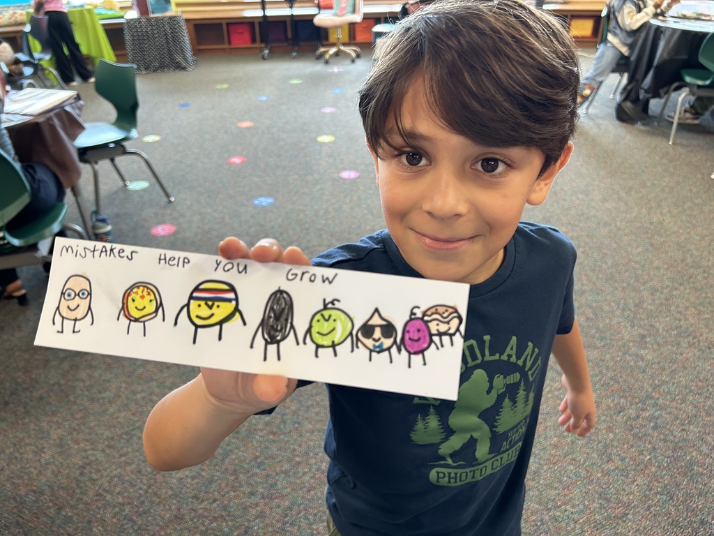 A young boy holds up a drawing of various smiling characters with captions, including "Help you grow."