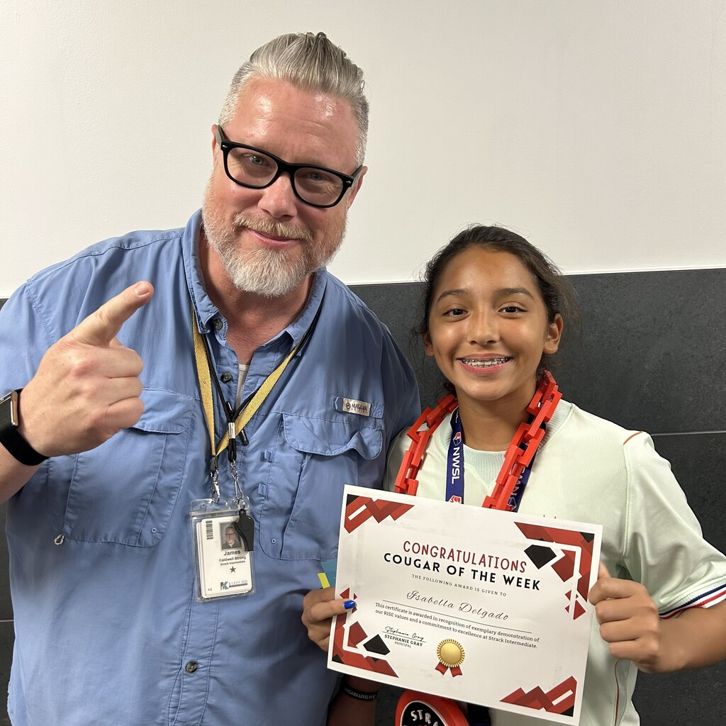 Man and a girl hold a certificate. The girl smiles, pointing at the text. Both wear ID lanyards.